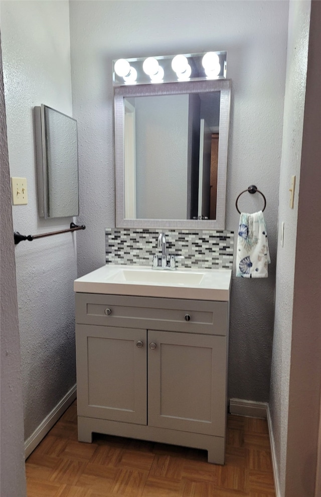 bathroom featuring vanity, parquet flooring, and backsplash