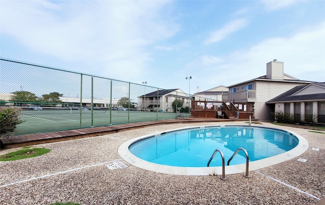 view of pool featuring tennis court and a wooden deck