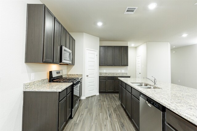 kitchen featuring dark brown cabinets, light wood-type flooring, stainless steel appliances, and sink