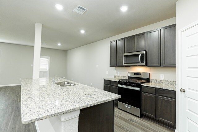 kitchen featuring an island with sink, sink, light wood-type flooring, and appliances with stainless steel finishes