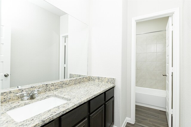 bathroom featuring hardwood / wood-style floors, vanity, and tiled shower / bath combo