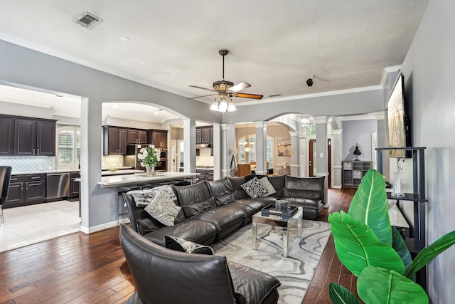 living room featuring wood-type flooring, decorative columns, ceiling fan, and ornamental molding