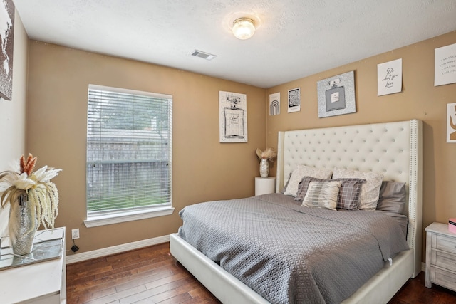 bedroom featuring a textured ceiling, dark hardwood / wood-style floors, and multiple windows