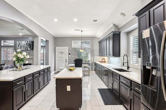 kitchen with backsplash, a wealth of natural light, a kitchen island, and appliances with stainless steel finishes