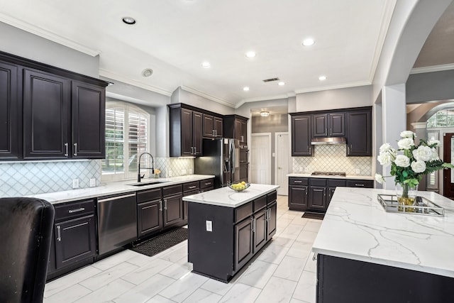 kitchen with sink, a kitchen island, a healthy amount of sunlight, and appliances with stainless steel finishes