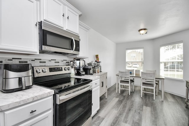 kitchen featuring light hardwood / wood-style floors, white cabinetry, decorative backsplash, and appliances with stainless steel finishes