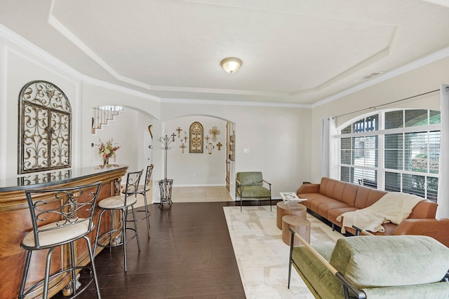 living room with a raised ceiling, dark hardwood / wood-style flooring, and ornamental molding