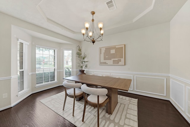 dining space with a chandelier, wood-type flooring, and a tray ceiling