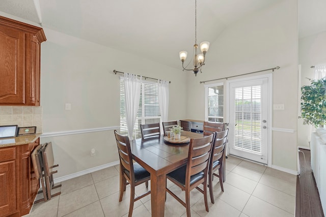 tiled dining space featuring a chandelier and vaulted ceiling