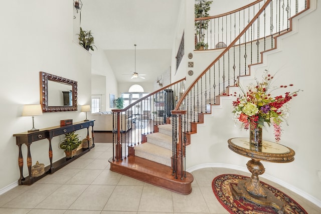 stairway featuring ceiling fan, tile patterned flooring, and high vaulted ceiling