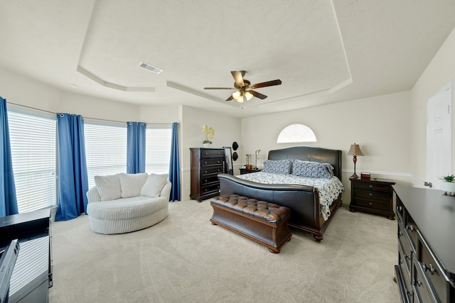 carpeted bedroom with ceiling fan and a raised ceiling