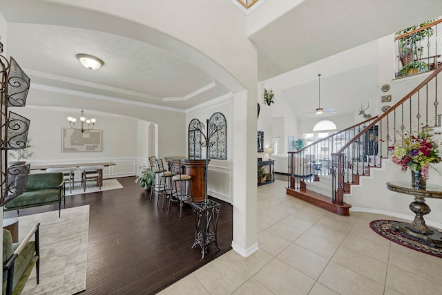 foyer entrance featuring vaulted ceiling, ceiling fan with notable chandelier, and light wood-type flooring