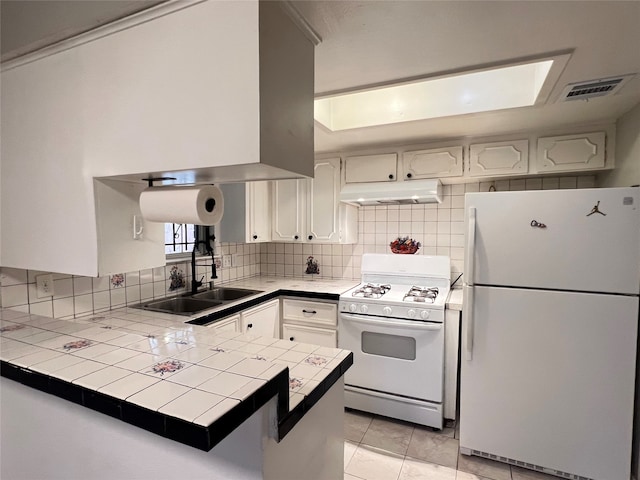 kitchen featuring tile counters, white cabinets, kitchen peninsula, tasteful backsplash, and white appliances