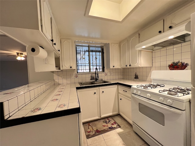 kitchen with white range with gas stovetop, white cabinetry, range hood, and tile counters