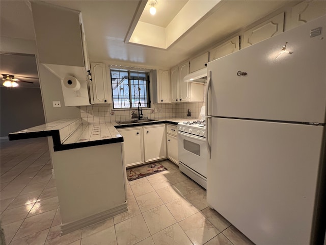 kitchen with white cabinets, kitchen peninsula, decorative backsplash, extractor fan, and white appliances