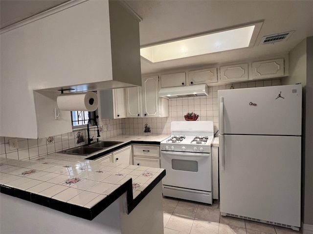 kitchen with white cabinetry, kitchen peninsula, tile countertops, and white appliances