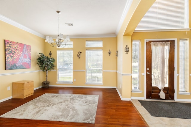 entrance foyer with a chandelier, dark hardwood / wood-style flooring, and ornamental molding