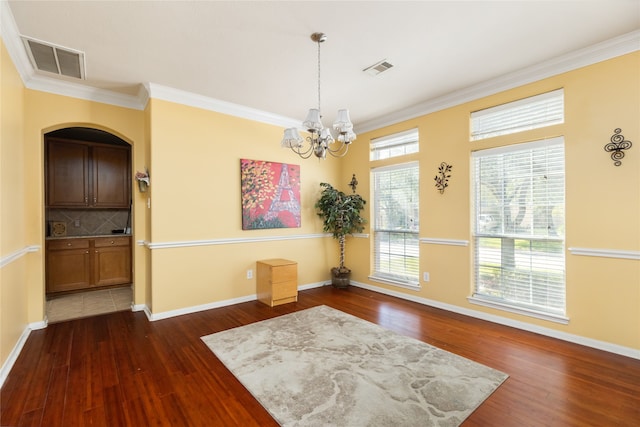 unfurnished dining area with ornamental molding, a chandelier, and dark hardwood / wood-style floors