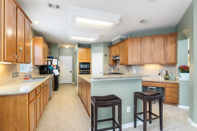 kitchen featuring backsplash, sink, black microwave, a breakfast bar area, and a center island