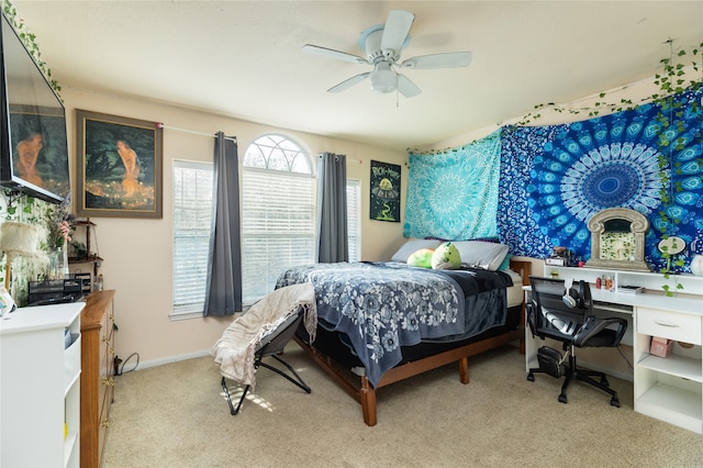 bedroom featuring built in desk, ceiling fan, and light colored carpet