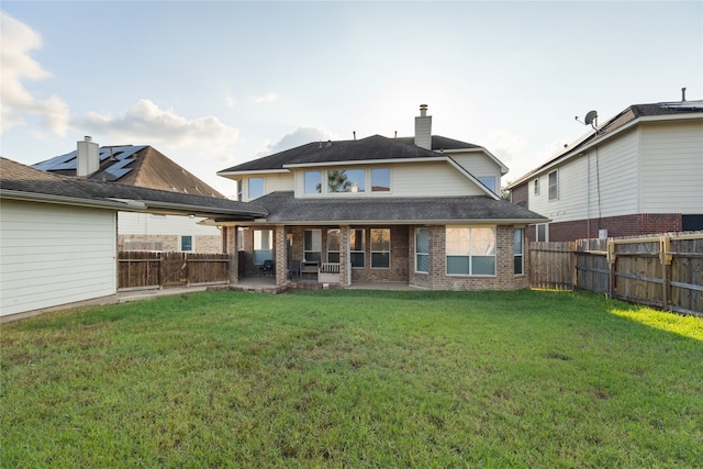 back of property with a lawn and a patio area