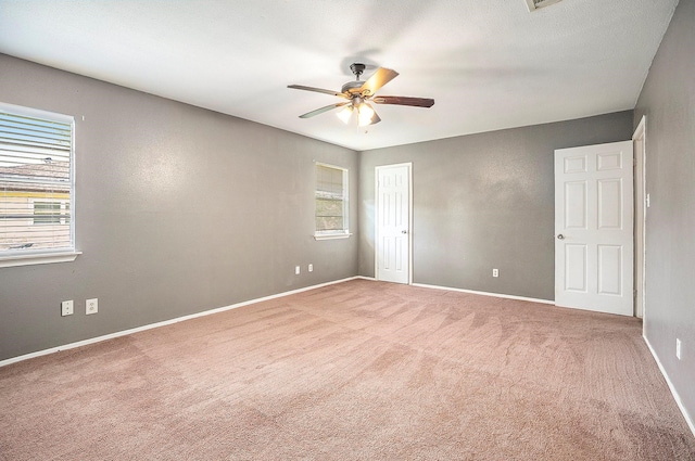 carpeted spare room featuring a wealth of natural light and ceiling fan