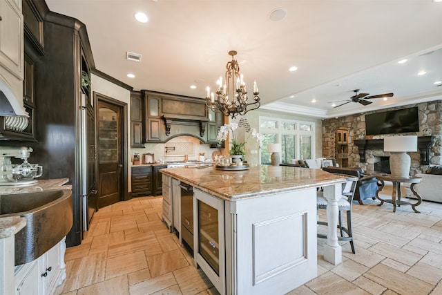 kitchen featuring a kitchen bar, backsplash, dark brown cabinets, a large island with sink, and decorative light fixtures