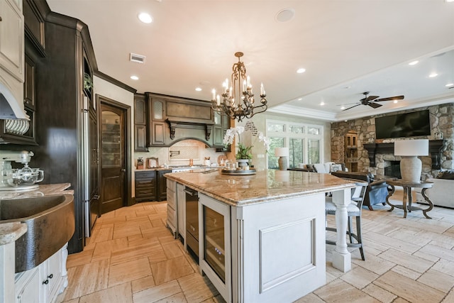 5015 Ossineke Ct, Spring, TX 77386 - kitchen featuring ornamental molding, a kitchen island, light stone counters, a stone fireplace, and beverage cooler