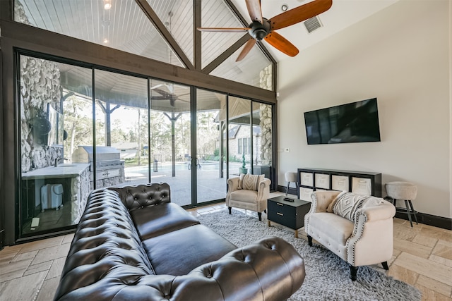 living room with a wealth of natural light, ceiling fan, sink, and high vaulted ceiling