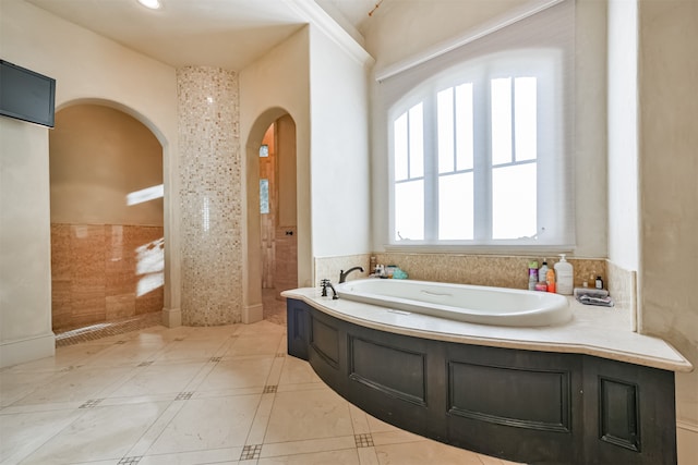 bathroom with a tub and tile walls