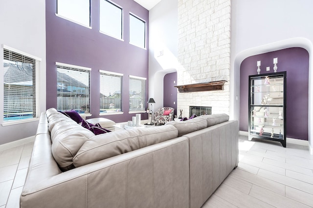 living room featuring light tile patterned flooring, a fireplace, and a high ceiling