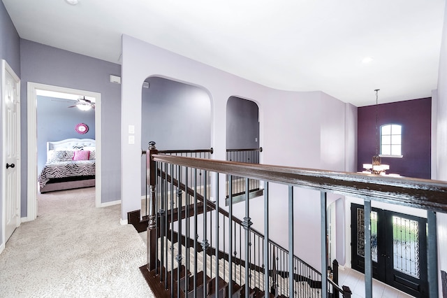 hallway featuring light carpet and a notable chandelier