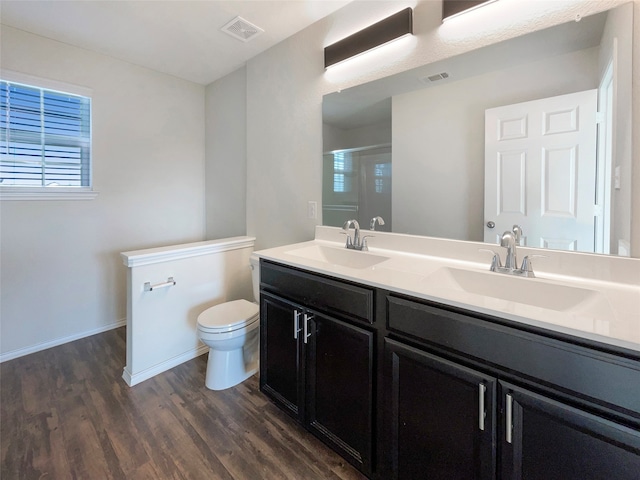 bathroom featuring toilet, vanity, wood-type flooring, and a shower with shower door