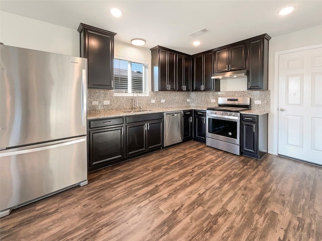 kitchen featuring stainless steel appliances, dark hardwood / wood-style floors, backsplash, and light stone countertops