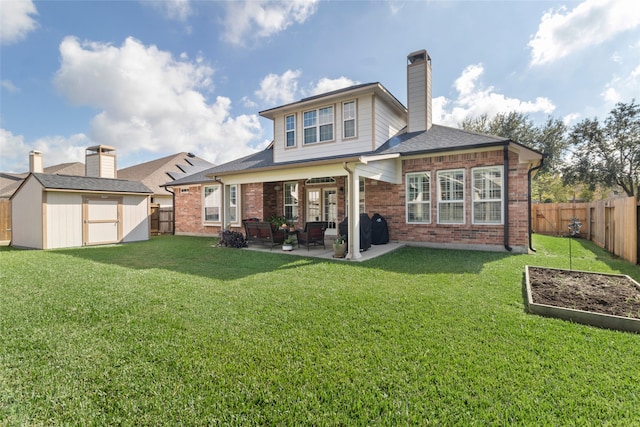 rear view of house with a patio, a lawn, and a storage unit