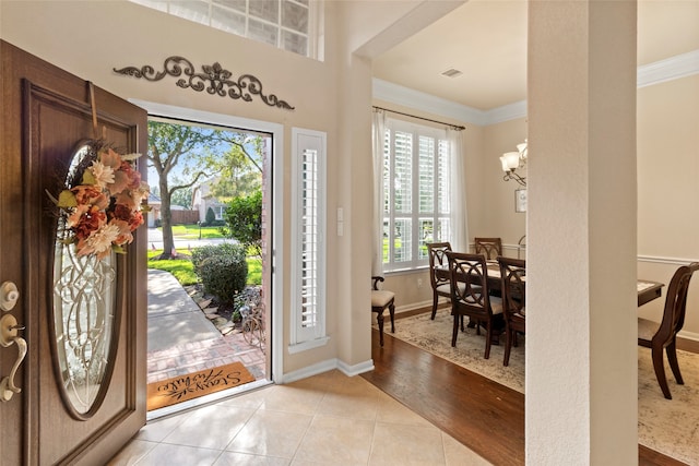 foyer with an inviting chandelier, a healthy amount of sunlight, light hardwood / wood-style flooring, and ornamental molding