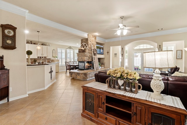 living room with crown molding, ceiling fan, a fireplace, and light tile patterned flooring