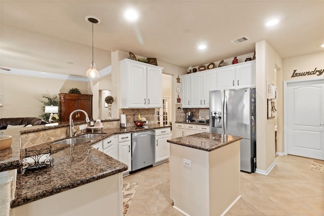 kitchen featuring dark stone counters, kitchen peninsula, hanging light fixtures, sink, and appliances with stainless steel finishes