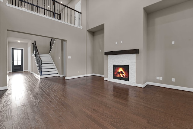 unfurnished living room featuring a fireplace, a high ceiling, and dark hardwood / wood-style flooring