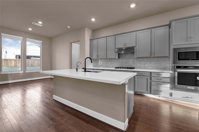 kitchen with dark hardwood / wood-style flooring, sink, an island with sink, and stainless steel appliances