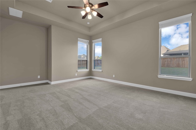 carpeted spare room featuring ceiling fan and a raised ceiling