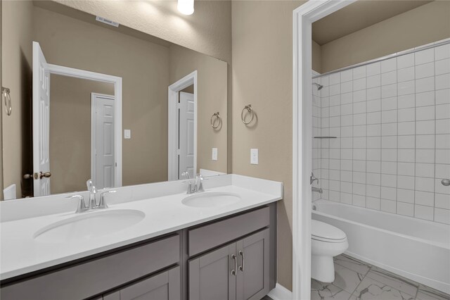 full bathroom featuring toilet, vanity, and tiled shower / bath