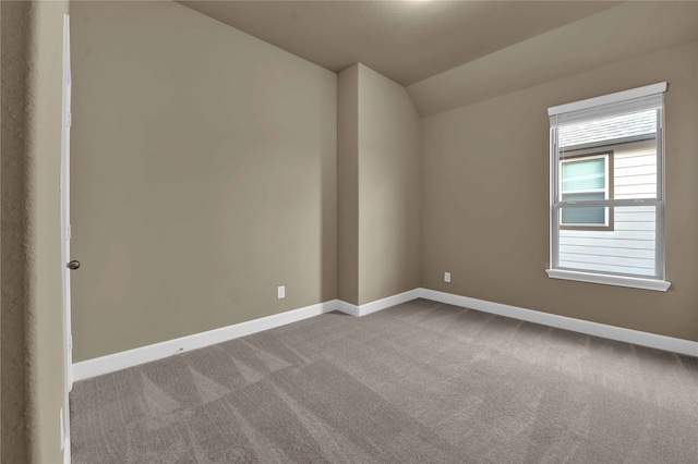 empty room featuring vaulted ceiling and light colored carpet