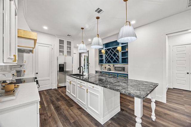 kitchen with sink, white cabinetry, appliances with stainless steel finishes, an island with sink, and dark stone counters