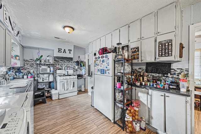 kitchen with decorative backsplash, a textured ceiling, sink, white cabinetry, and white appliances