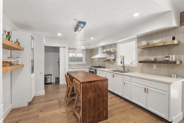 kitchen featuring butcher block countertops, light wood-type flooring, sink, white cabinets, and a center island