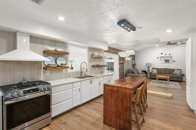 kitchen featuring white cabinetry, extractor fan, sink, gas stove, and a kitchen island