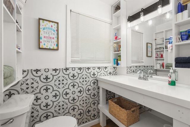 bathroom with sink, toilet, and tile walls