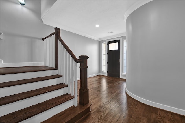 foyer entrance with dark wood-type flooring and crown molding