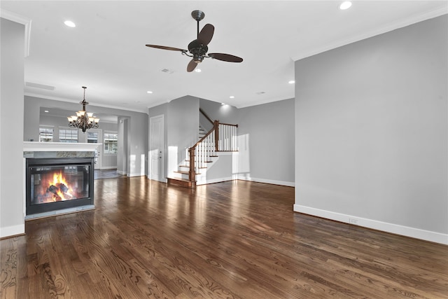 unfurnished living room with dark wood-type flooring, a fireplace, ceiling fan with notable chandelier, and crown molding